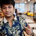 close up portrait young male indian freelancer fast food cafe handsome head asian man wear shirt comfortable coffee shop shows two fingers sign