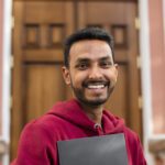 front view smiley man holding book scaled e1744107888605